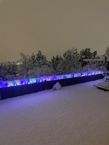 a fence covered in snow with blue and purple lights at Charming Private Home with Hot Tub and Esja Mountain View in Mosfellsbær