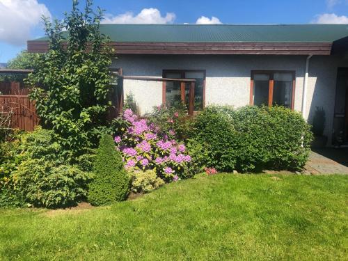 a house with bushes and flowers in front of it at Charming Private Home with Hot Tub and Esja Mountain View in Mosfellsbær
