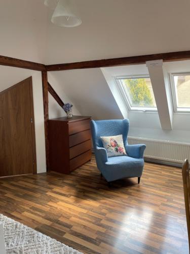 a living room with a blue chair and a window at Penzion Agape in Luhačovice
