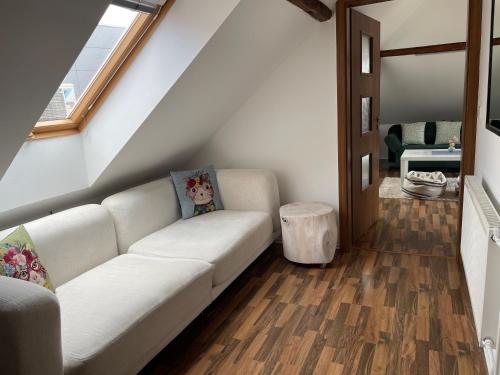 a living room with a white couch and wooden floors at Penzion Agape in Luhačovice