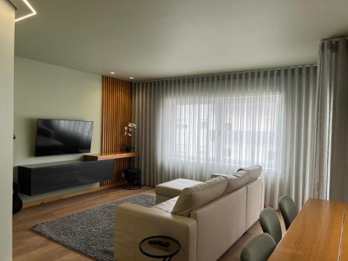 a living room with a couch and a television at Casa de Lencastre, Refúgio elegante entre tradição e modernidade in Viana do Castelo