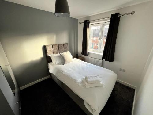 a bedroom with a bed with white sheets and a window at Kingfisher House by Blue Skies Stays in Stockton-on-Tees