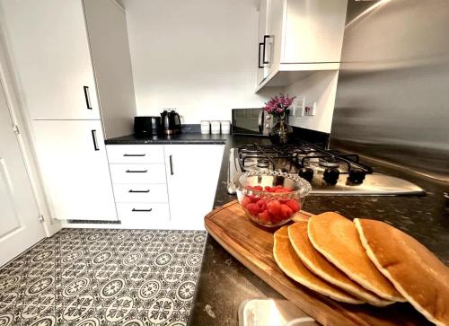 a kitchen with a counter with a bowl of fruit on a cutting board at Whessoe House by Blue Skies Stays in Stockton-on-Tees