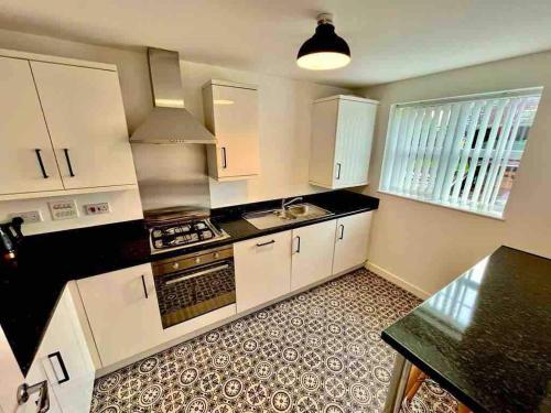 a kitchen with white cabinets and a stove top oven at Whessoe House by Blue Skies Stays in Stockton-on-Tees