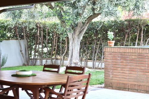 a wooden table and chairs in a yard with a tree at Villa Gialla in Porto Recanati