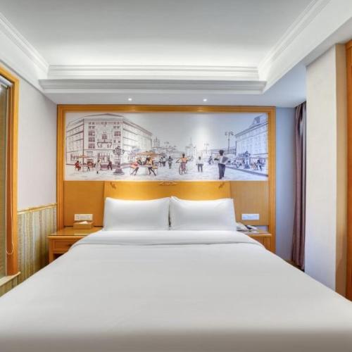 a bedroom with a large bed with a painting on the wall at Vienna 3 Best Hotel Fuzhou Fuma Road Ziyang in Fuzhou