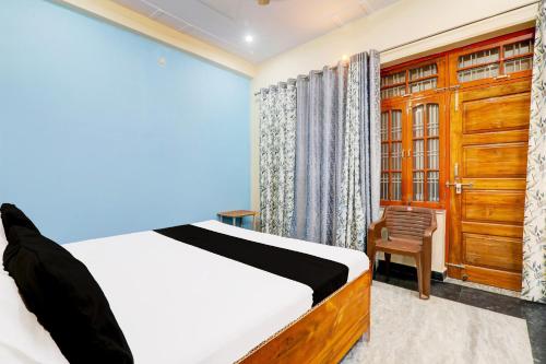 a bedroom with a bed and a chair and a window at Hotel O Heaven Inn in Lucknow