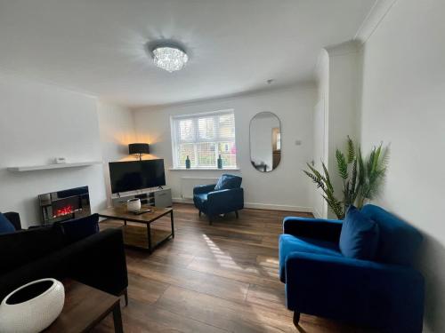 a living room with blue couches and a tv at Cotswold House in Stockton-on-Tees