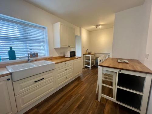 a kitchen with white cabinets and a sink and a window at Cotswold House in Stockton-on-Tees