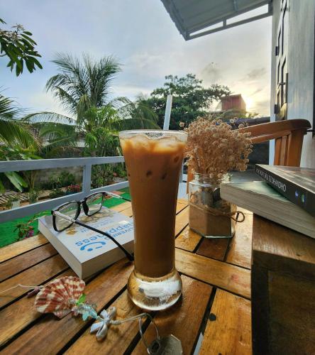 a drink sitting on a wooden table with a book at Muối Homestay in Ấp Khánh Phước (1)
