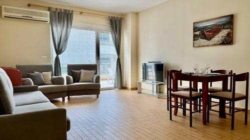 Una sala de estar con un sofá y una mesa con sillas. en Your Comfy Apartment, en Sarandë