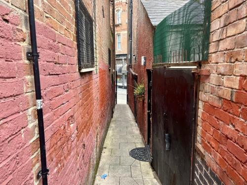 an alley with a red brick wall and a door at Chic 1-Bed Hideaway in Hockley in Nottingham