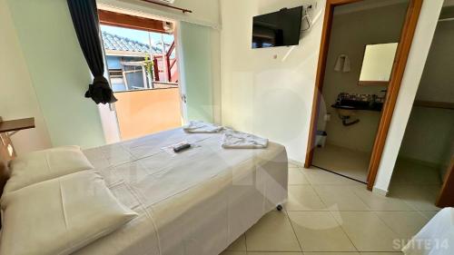 Una cama blanca en una habitación con ventana. en Pousada Werneck Residence Suites, en Ubatuba