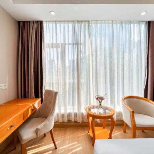 a room with a desk and chairs and a large window at Vienna 3 Best Hotel Fuzhou Fuma Road Ziyang in Fuzhou