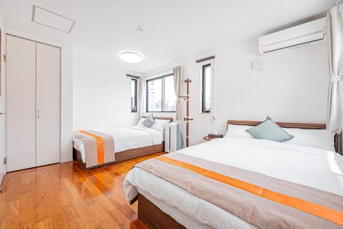 two beds in a room with white walls and wood floors at Ikebukuro Shopping Street 3BR in Tokyo