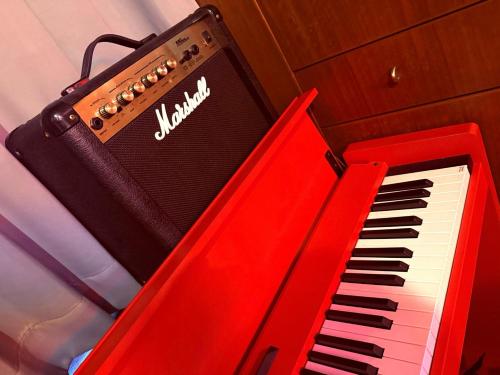 a red piano sitting next to a black and white keyboard at GRAND HOTEL SHISA St OKINAWA グランドホテル シーサーストリート沖縄 in Urazoe