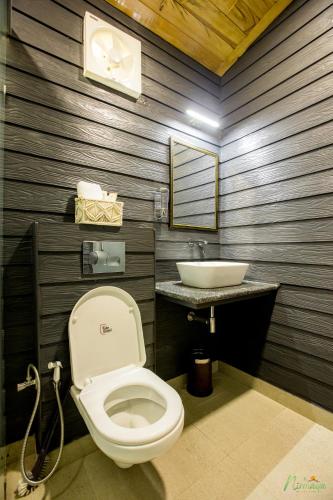 a bathroom with a toilet and a sink at Nirmaya Resort in Kanatal