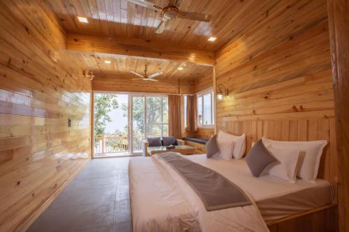 una camera da letto con un grande letto in una camera in legno di Nirmaya Resort a Kanatal