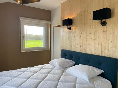 une chambre avec un grand lit blanc avec une fenêtre dans l'établissement Les gites du champ des oiseaux, à Saint-Amand-les-Eaux