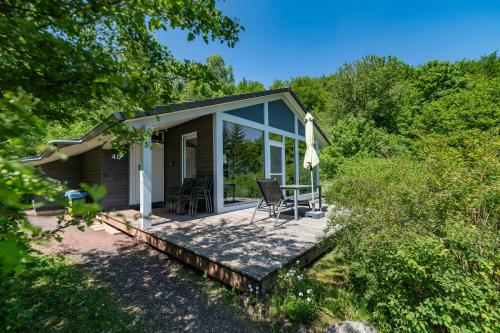 a small cottage with a deck with a table and chairs at 4 Personen mit Sauna F4H0 in Ruhla