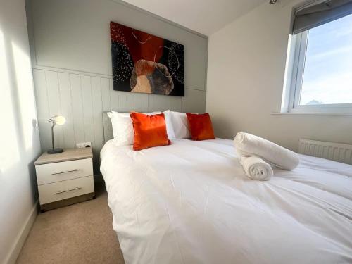 a bedroom with a white bed with orange pillows at Ruby Place by Blue Skies Stays in Hartlepool