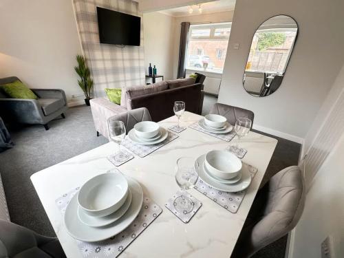 a dining room table with plates and glasses on it at Corfe House by Blue Skies Stays in Stockton-on-Tees