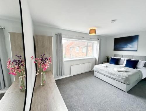 a bedroom with a bed and a window with flowers in vases at Corfe House by Blue Skies Stays in Stockton-on-Tees