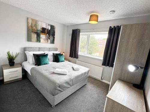 a bedroom with a bed with green pillows and a window at Corfe House by Blue Skies Stays in Stockton-on-Tees