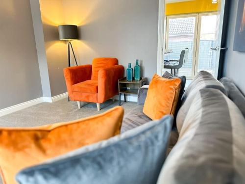 a living room with a couch and an orange chair at Mable House by Blue Skies Stays in Redcar