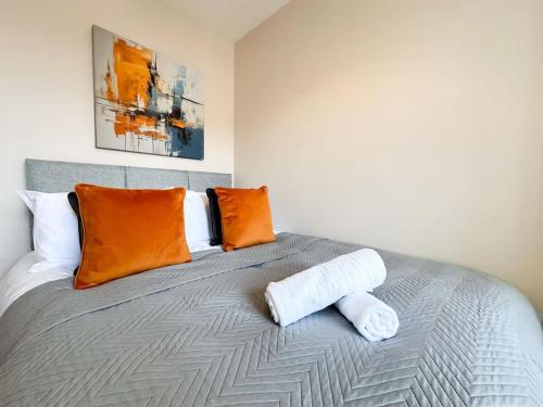 a bedroom with a bed with orange and white pillows at Mable House by Blue Skies Stays in Redcar