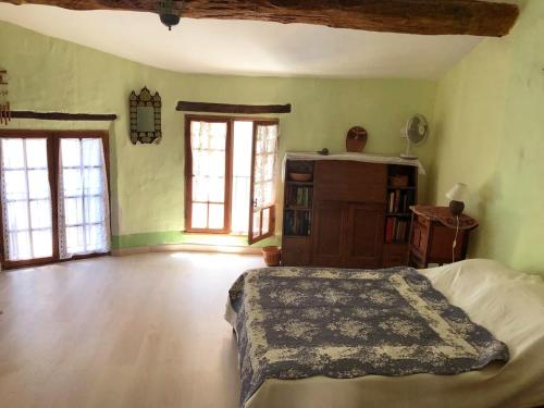 une chambre avec un lit et deux fenêtres dans l'établissement Maison de la Fontaine, à Saint-Roman-de-Malegarde