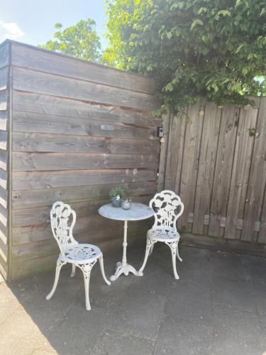 a table and two chairs next to a fence at Queens Romantic Beachhouse in Zandvoort