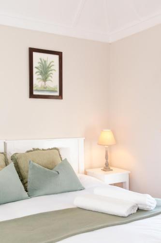 a bedroom with a white bed with a plant picture on the wall at Botha House in Pennington