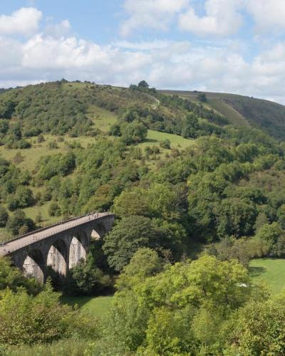 a train is crossing a bridge over a hill at Rock Mill 1 Bed Apartment 32 in Stoney Middleton