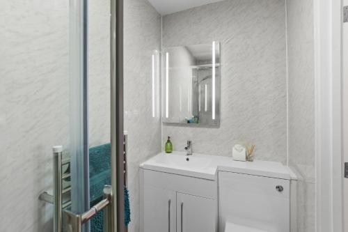 a white bathroom with a sink and a mirror at The Old Workshop - North East Escapes in Wooler