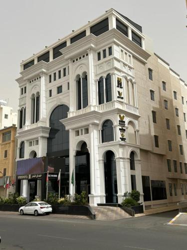 a white building with a car parked in front of it at Vender Hotel in Taif