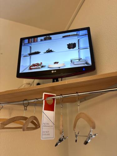 une télévision à écran plat installée au-dessus d'une étagère. dans l'établissement ibis budget Belfort Centre, à Belfort