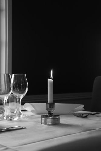 a candle sitting on top of a table with glasses at Åhus Gästgivaregård in Åhus