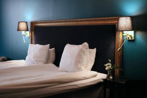a bedroom with a bed with white sheets and pillows at Åhus Gästgivaregård in Åhus