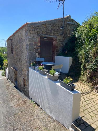 un bâtiment en pierre avec des plantes en pot sur un mur dans l'établissement Le petit moulin, à Pouzauges