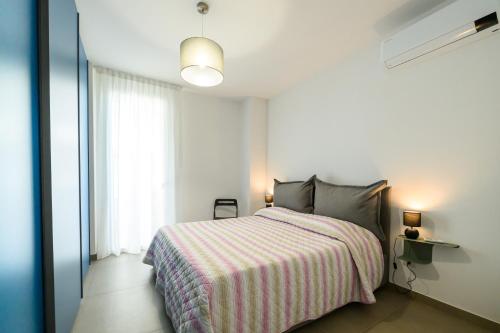 ein Schlafzimmer mit einem Bett mit gestreifter Decke und einem Fenster in der Unterkunft Appartamento - Brand New Luxury Apartment - Giardini Naxos, Recanati in Giardini-Naxos