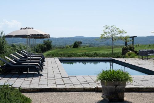 une piscine avec des chaises longues et un parasol dans l'établissement Gîte Figuier au Mas Dujau, à Saint-Sauveur-de-Cruzières