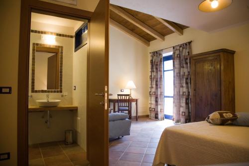 a bedroom with a bed and a bathroom with a sink at Agriturismo Bio-Ecologico Sant'Isidoro in Roccaforte Mondovì