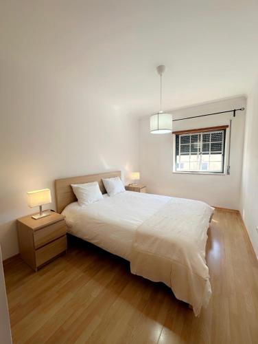 a white bedroom with a large bed and a window at Elegant Getaway II - Lisbon- 2 bedroom apartment in Montijo in Atalaia