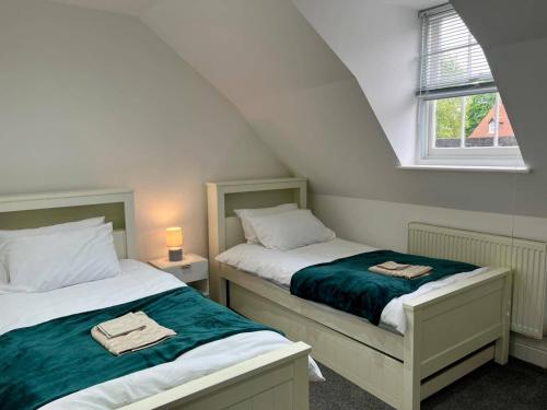 two beds in a small room with a window at Spacious 4-Bedroom House - Garden & Free Parking in Faversham