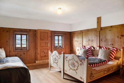 a bedroom with two beds and wooden walls at Berghof Moosen in Hart im Zillertal