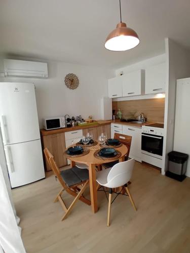une cuisine avec une table et des chaises et un réfrigérateur blanc dans l'établissement La Pinède entre village et plage Saint Cyr sur Mer, à Saint-Cyr-sur-Mer