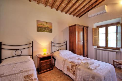 Un dormitorio con dos camas y una ventana. en Villa Picchio by PosarelliVillas, en Volterra