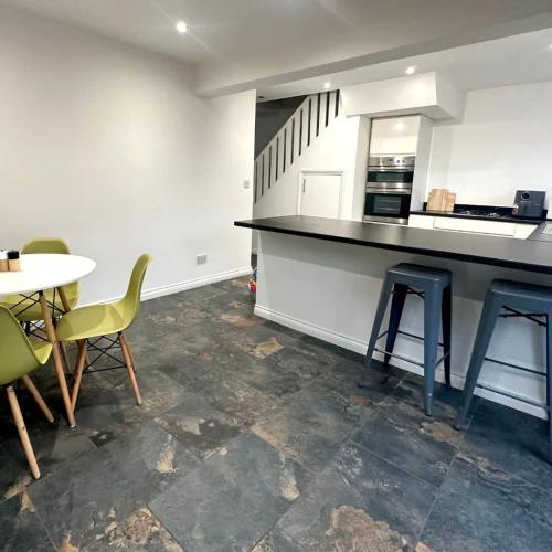 a kitchen with a counter and chairs and a table at Carew Place by Blue Skies Stays in Seaton Carew