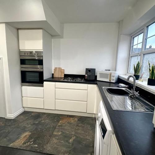 a kitchen with white cabinets and a black counter top at Carew Place by Blue Skies Stays in Seaton Carew